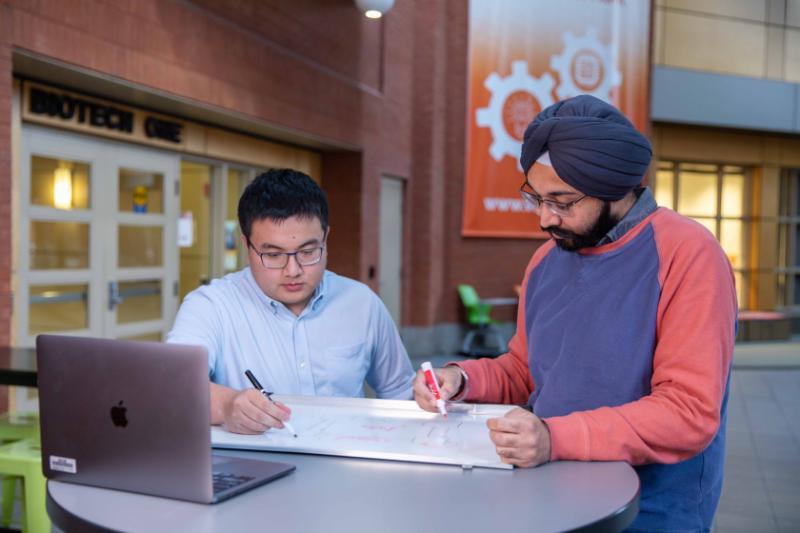 Two students studying outside of a biotech building.